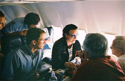 Secretary O'Neill, Bono, Undersecterary John Taylor (foreground) and Treasury Chief of Staff Tim Adams (left) discuss conclusions of the Africa trip on the return flight from Addis Ababa, Ethiopia.