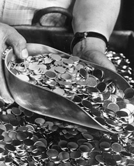 Black and white photograph of hands and scoop gathering coins.